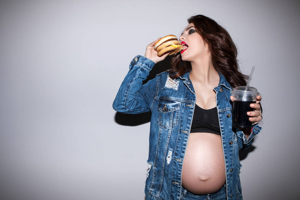 Portrait of pregnant woman eating burger - Foto, Bild
