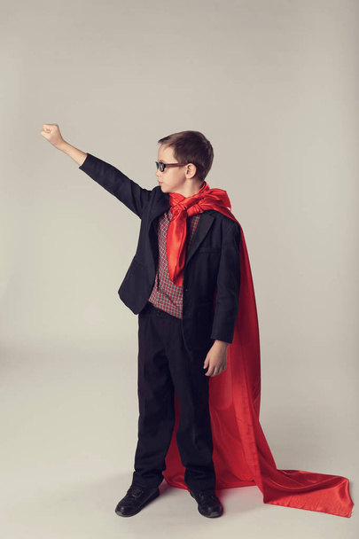 Jovem menino de negócios de terno e capa de super-herói vermelho
 - Foto, Imagem