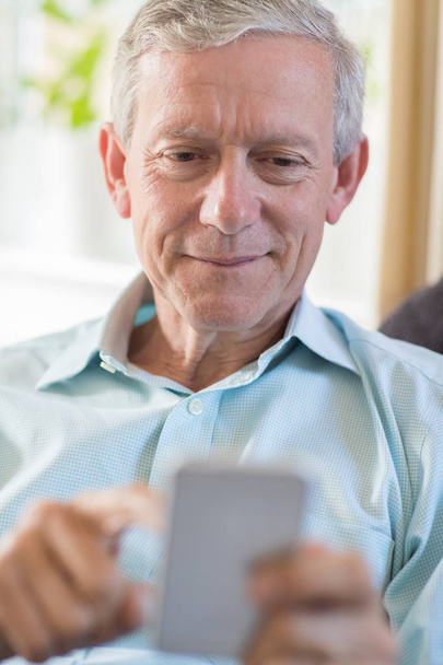 Mature Man At Home Sending Text Message On Mobile Phone - Foto, imagen