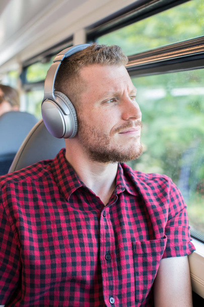 Young Man Listening To Music On Headphones During Journey To Wor - Foto, Imagem