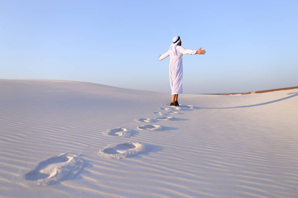 Joyful male Muslim walks through white sand desert and enjoys li - Fotoğraf, Görsel