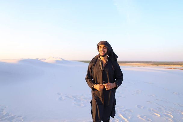 Счастливый арабский парень, ходит по пустыне, улыбается и наслаждается ли
 - Фото, изображение