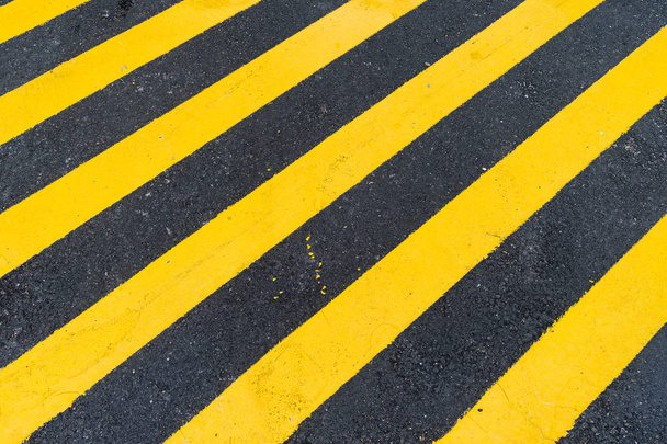 Fondo de asfalto con franja diagonal de advertencia negra y amarilla
 - Foto, imagen