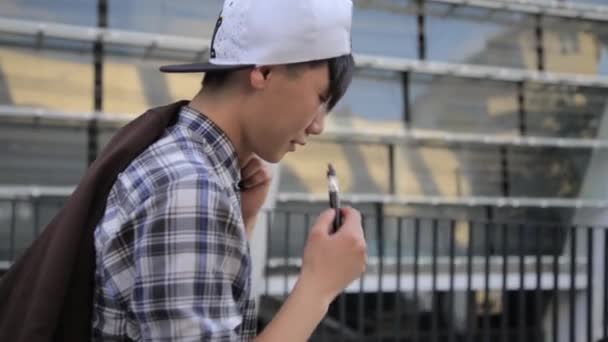 Young Man Walking On The Street And Smoke E-Cigarette. Vape - Filmati, video