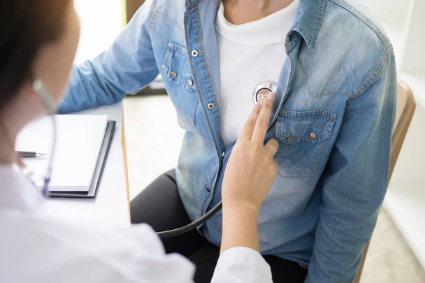 Medico ascoltando allegri giovani pazienti petto con stetoscopio
 - Foto, immagini