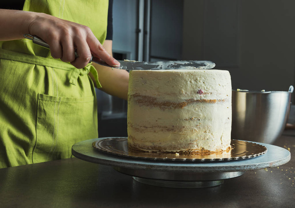Unrecognisable woman decorating a delicious layered sponge cake with icing cream - Foto, imagen