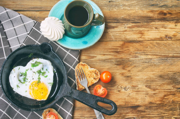 Fried eggs in frying pan, toast heart shape, cup of coffee - Photo, image