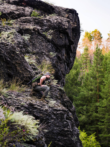 ρωσικό sniper που ετοιμάζεται να χτυπήσει τον εχθρό μέσα στο δάσος, στο βουνό, στρατιωτική έννοια του πολέμου - Φωτογραφία, εικόνα