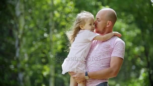 Iloinen isä halailee ja heiluttaa tyttäriään puistossa, hidastettuna
 - Materiaali, video