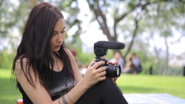 Młody mieszanej rasy kobiet indie filmowiec fotografowania w zielonym otoczeniu przyrody z trawy na tle - Materiał filmowy, wideo