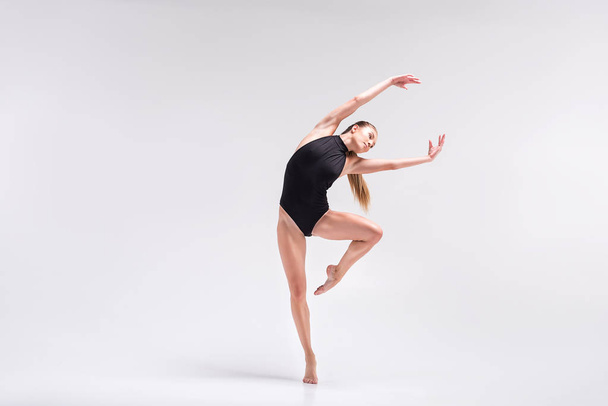Serious young woman performing element of gymnastics choreography - Foto, imagen
