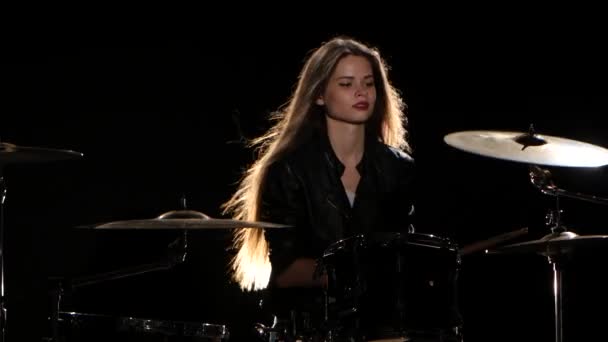Drummer girl starts playing energetic music, she smiles. Black background - Materiał filmowy, wideo