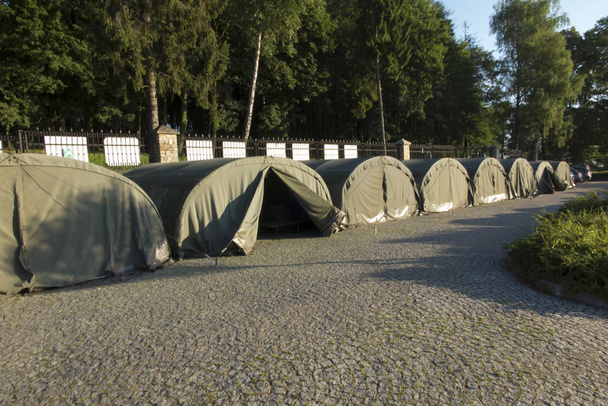 várias grandes tendas militares na área pavimentada
  - Foto, Imagem