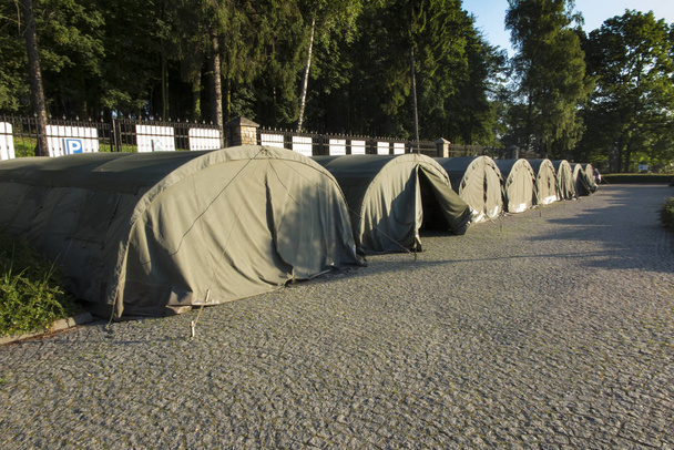 plusieurs grandes tentes militaires sur la zone pavée
  - Photo, image