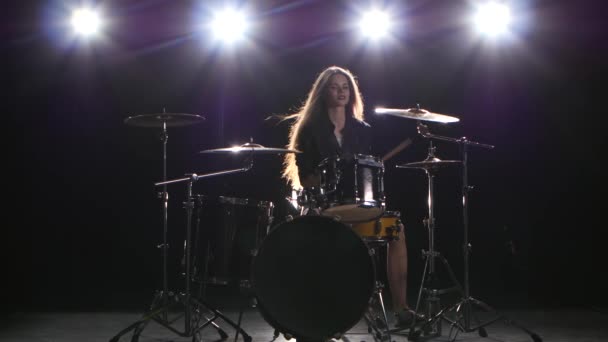 Drummer girl starts playing energetic music, she smiles. Black background - Záběry, video