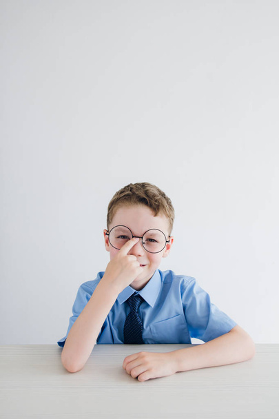 Schoolboy in school uniform and glasses sitting at the Desk - Photo, Image