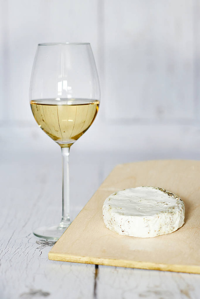 Glass of white wine and camembert cheese on a wooden background - Фото, зображення