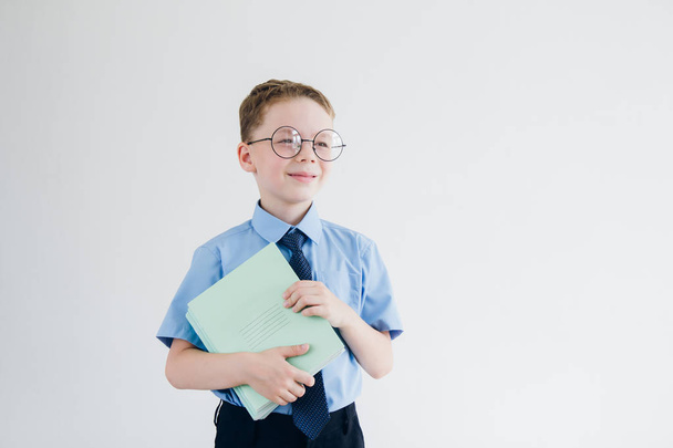 Schoolboy in school uniform and glasses, holding a stack of note - Foto, immagini
