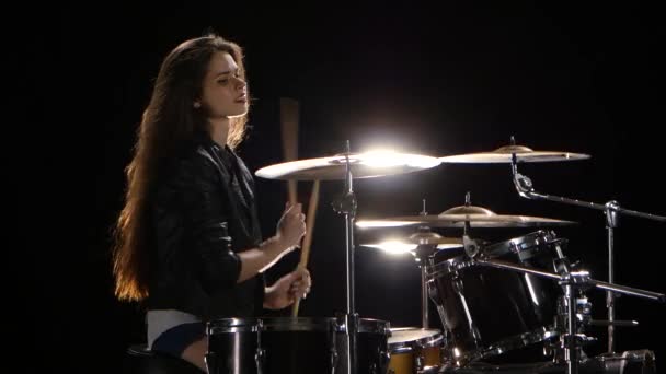 Girl drummer with chopsticks beats rhythmic music. Black background. Side view - Footage, Video