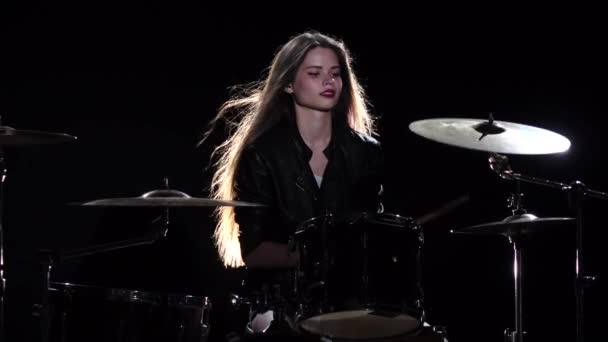 Drummer girl starts playing energetic music, she smiles. Black background. Slow motion - Video, Çekim