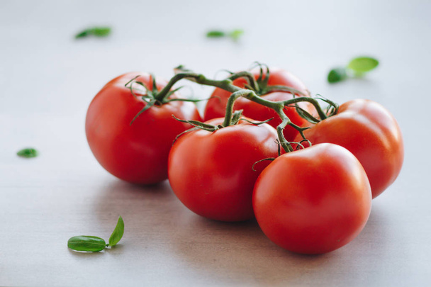 Ramo de tomates orgânicos frescos e pequenas folhas de manjericão
 - Foto, Imagem