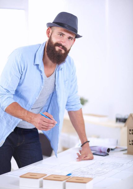 Portrait of male designer in hat with blueprints at desk - Foto, immagini