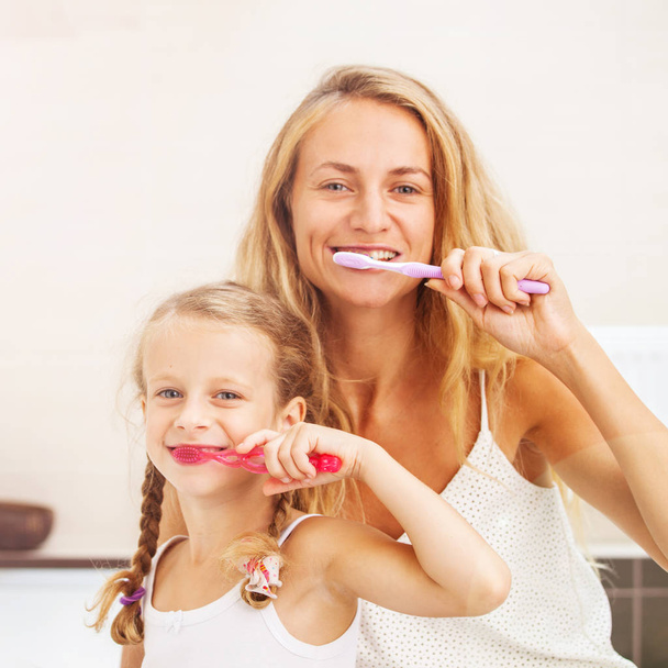 Mother and daughter brushing their teeth - Фото, зображення
