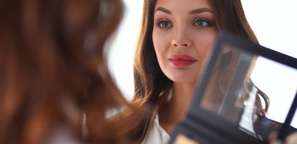 Young beautiful woman making make-up near mirror - Fotó, kép