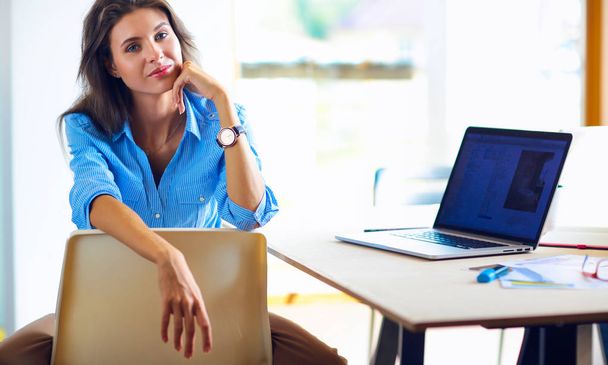 Young woman sitting at office table with laptop - Photo, image