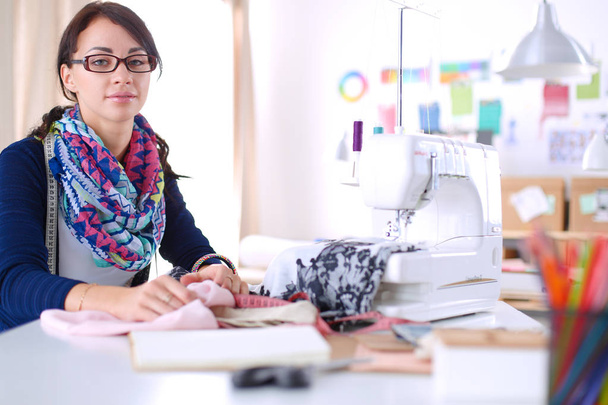 Young dressmaker designing clothes pattern on paper . - Foto, imagen