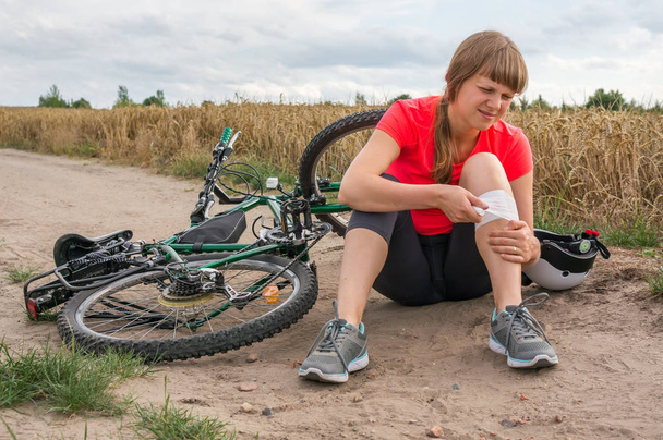 Mulher com dor no joelho depois de cair da bicicleta
 - Foto, Imagem