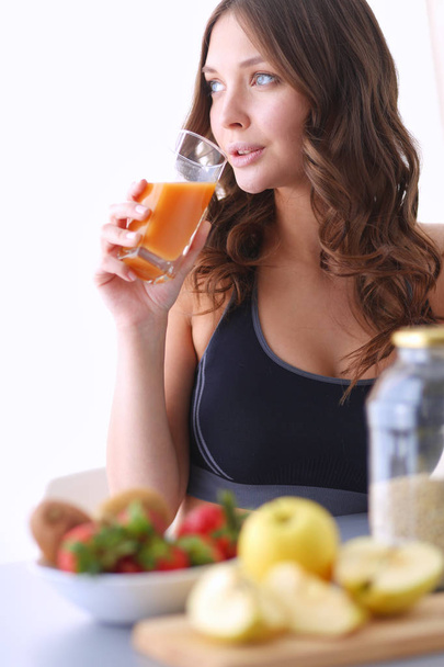 Girl sitting in the kitchen on the desk with fruit and glasses with juice. - Foto, imagen