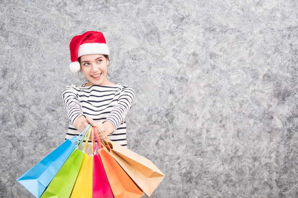 Schöne junge Mädchen mit Weihnachtsmütze hält viele Einkaufstüten in der Weihnachtszeit - Foto, Bild