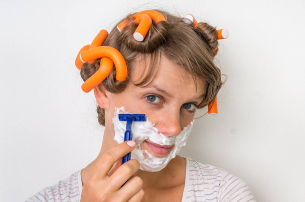 Mujer joven se afeita la cara con espuma y afeitadora
 - Foto, imagen