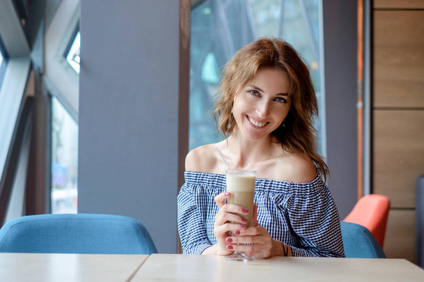pretty young woman sitting in a cafe with a cup of coffee latte - Photo, Image