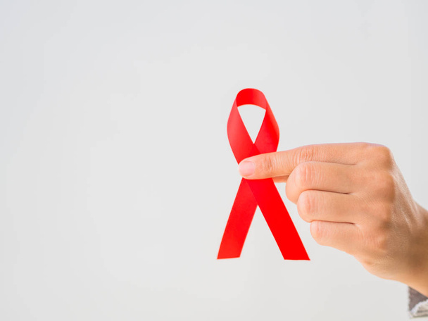 Vértes tartó piros szalag Hiv, világ Aids nap tudatosság szalag női kezek. Egészségügy és az orvostudomány koncepció. - Fotó, kép