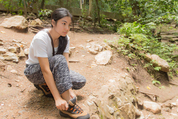 Femme asiatique attacher sa chaussure dans la forêt
 - Photo, image