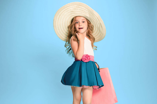 The cute little caucasian brunette girl in dress holding shopping bags - Valokuva, kuva