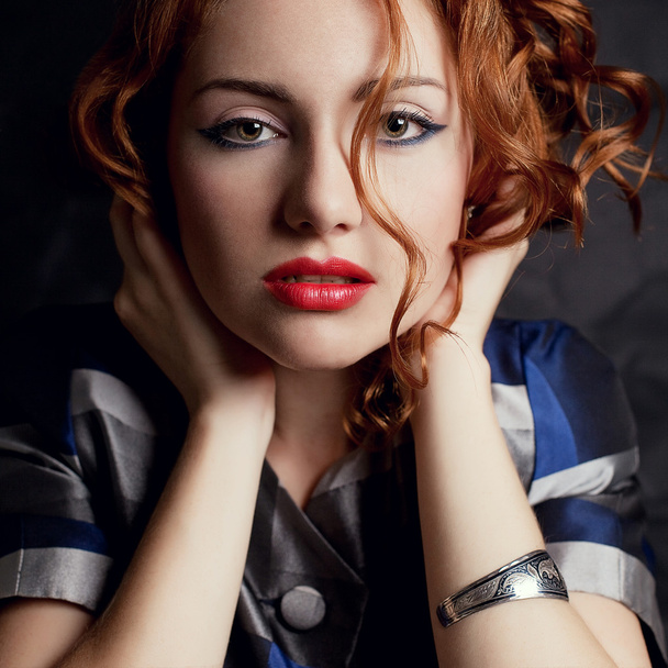 A beautiful young red-haired model in an arty jacket with metal - Фото, изображение