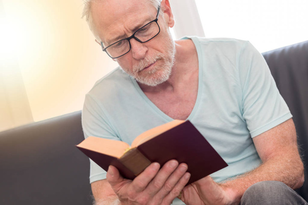 Portrait of mature man reading a book, light effect - Fotó, kép