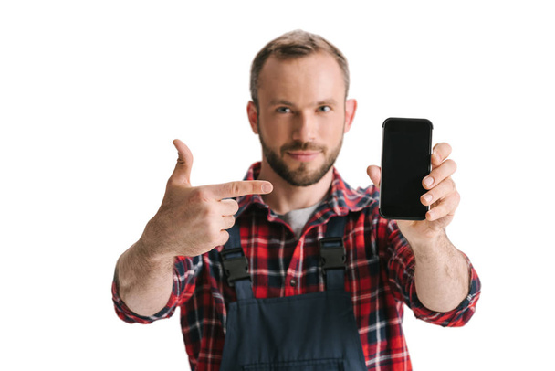 man in overall pointing at smartphone - Φωτογραφία, εικόνα