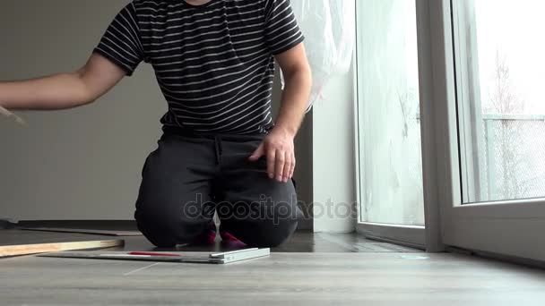 Careful craftsman man installing wooden laminate floor board at home - Footage, Video