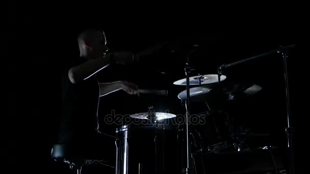 Good music in the perfomance of a professional drummer. Side view. Black background. Slow motion - Záběry, video