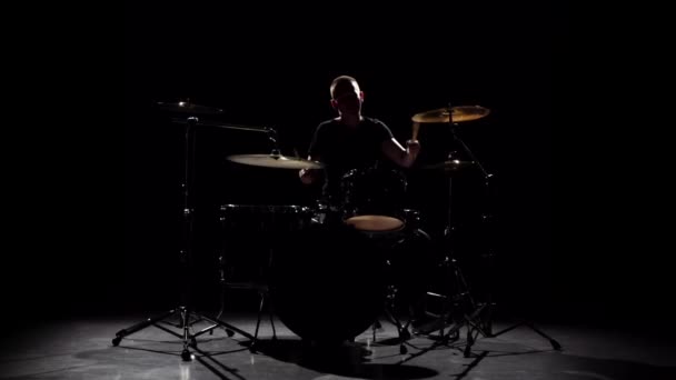 Professional musician plays music on drums with the help of sticks. Black background. Silhouette. Slow motion - Metraje, vídeo