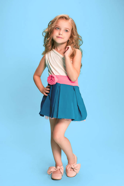 Longitud completa de hermosa niña en vestido de pie y posando sobre fondo azul
 - Foto, Imagen
