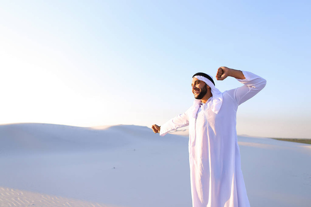 Szczęśliwy facet muzułmańskich spacery po połacie pustyni i spoczywa - Zdjęcie, obraz