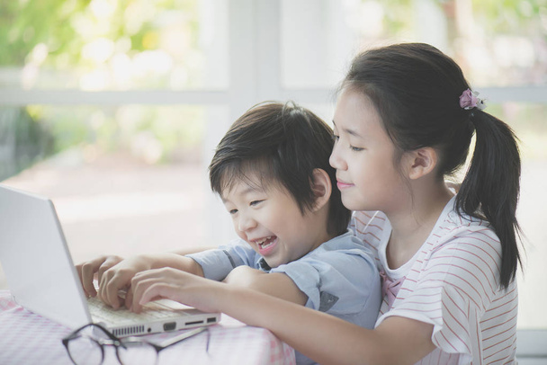 Lindos niños asiáticos usando tableta juntos
 - Foto, imagen