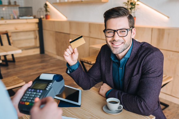 бізнесмен платить кредитною карткою в кафе
 - Фото, зображення