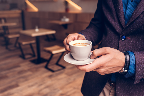 businessman holding cup of coffee in cafe - Фото, зображення