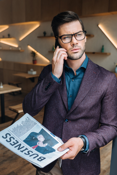 businessman with newspaper talking on smartphone - Foto, Bild